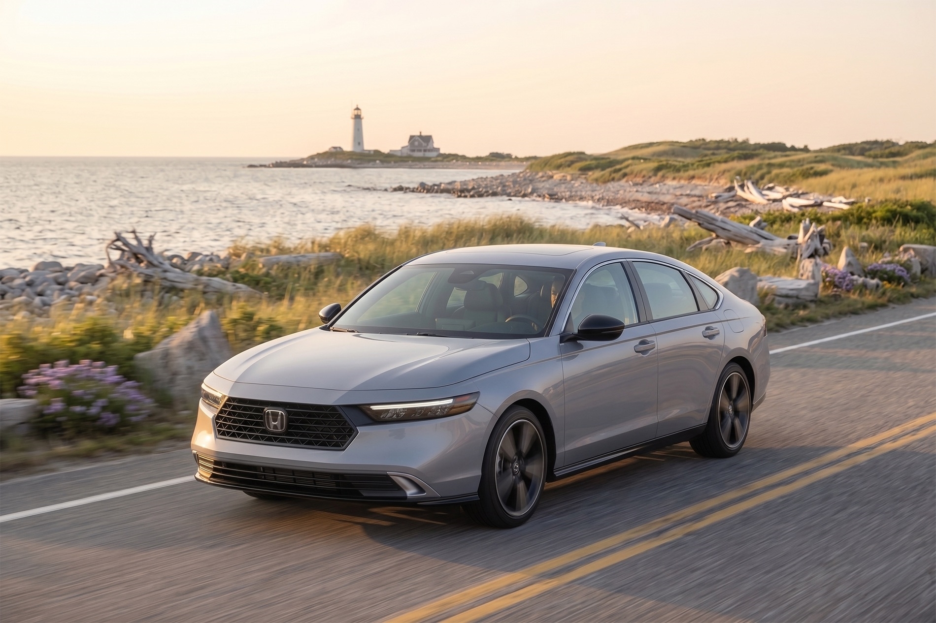 2026 Honda Accord cruising along a coastal South Shore Massachusetts road at sunset, with ocean shoreline, beach grass, driftwood, and a distant lighthouse in the background under warm golden-hour light
