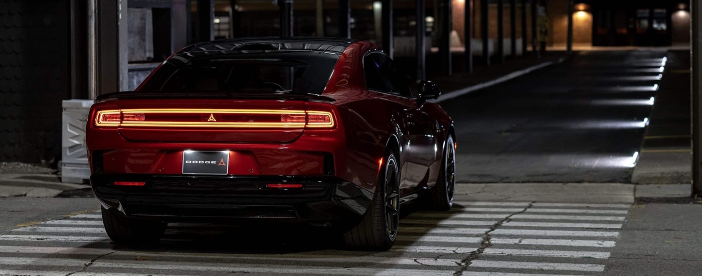 Rear of a red 2025 Dodge Charger driving in a city.