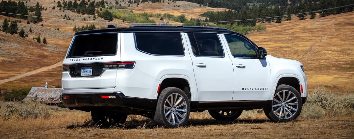 Side of a white 2025 Jeep Grand Wagoneer parked off-road in a field.