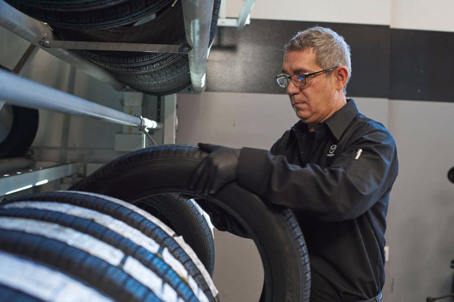 Mazda technician pulling a tire from a tire rack