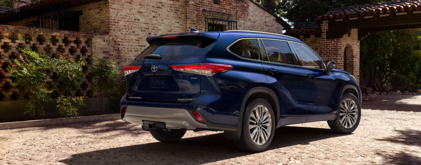 Blue 2026 Toyota Highlander parked in front of a house from the rear