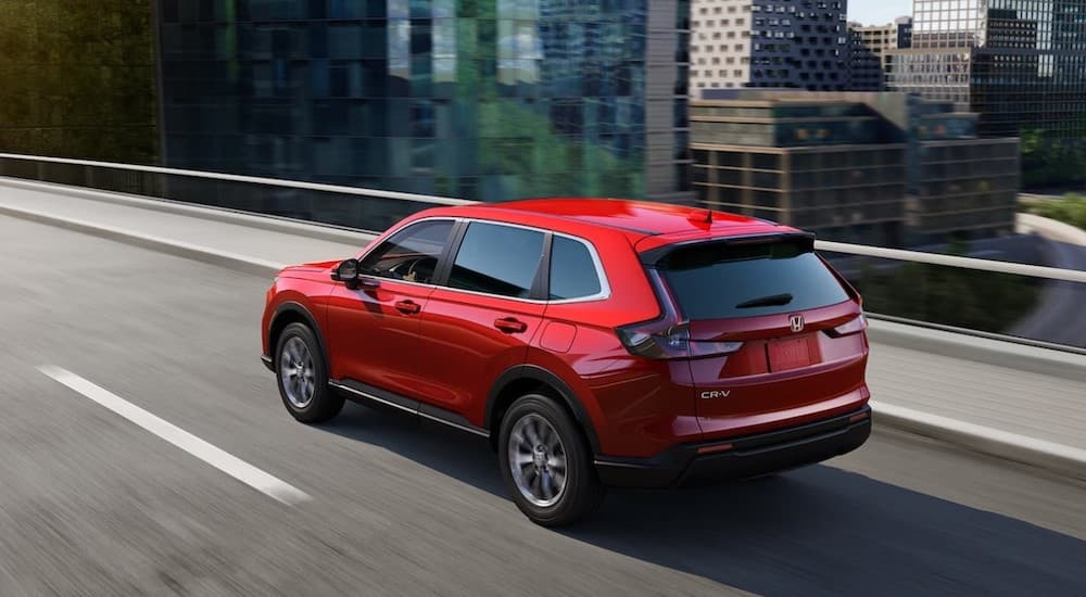 A red 2023 Honda CR-V driving on a bridge.