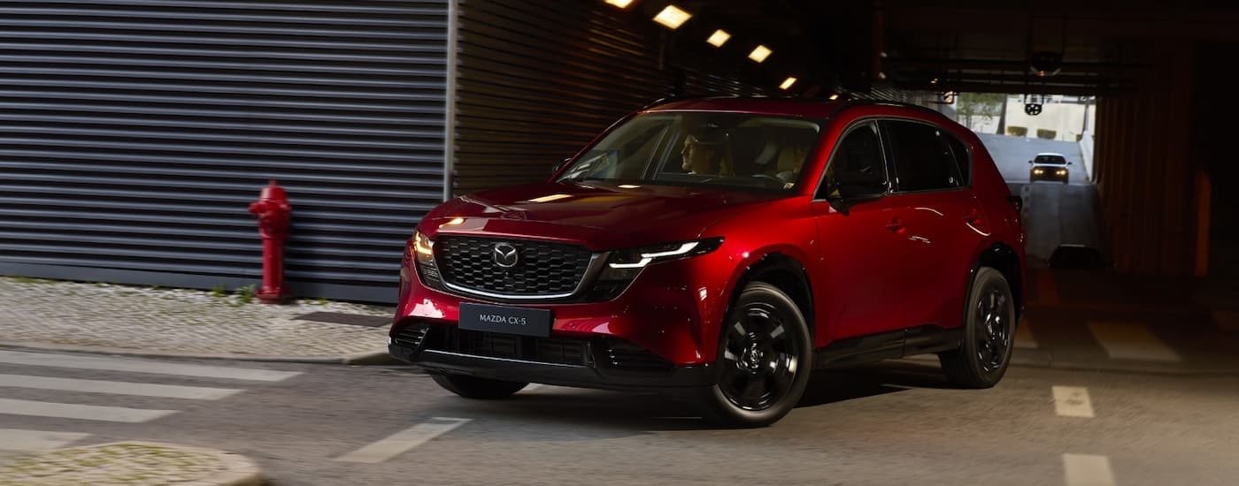 Red 2026 Mazda CX-5 driving around a bend.