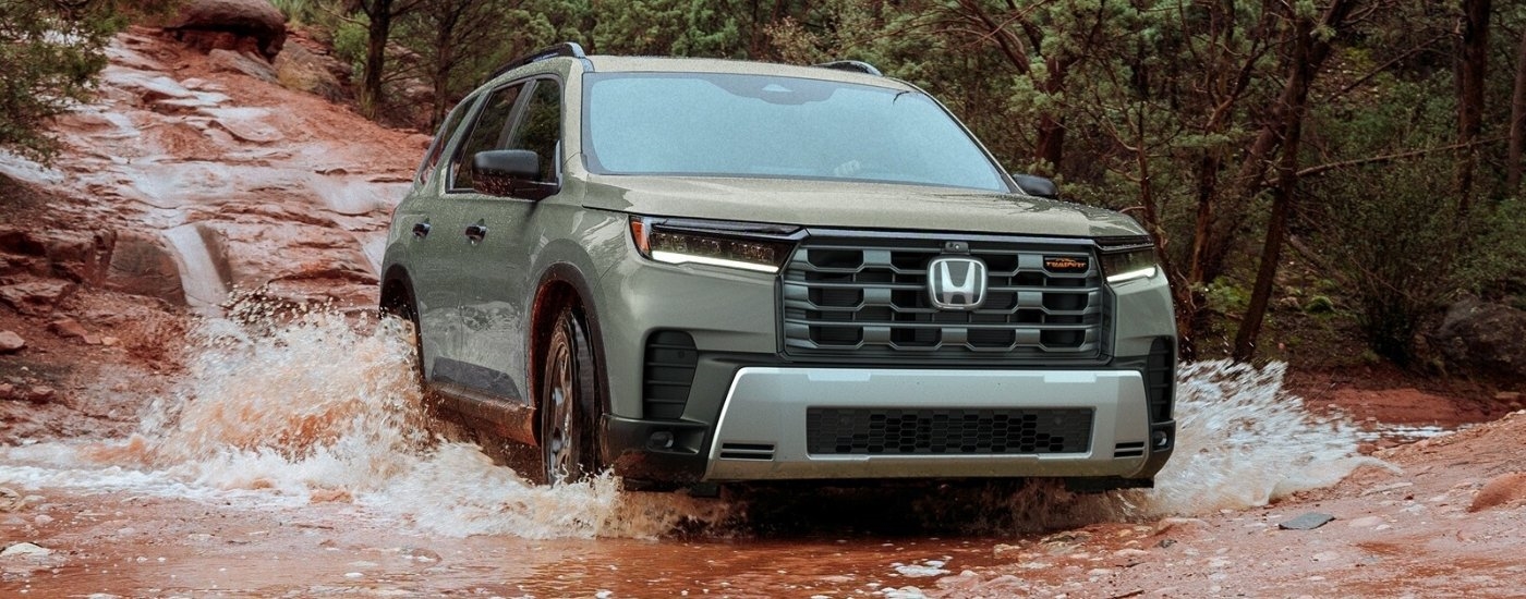 Green 2026 Honda Pilot TrailSport driving through a river