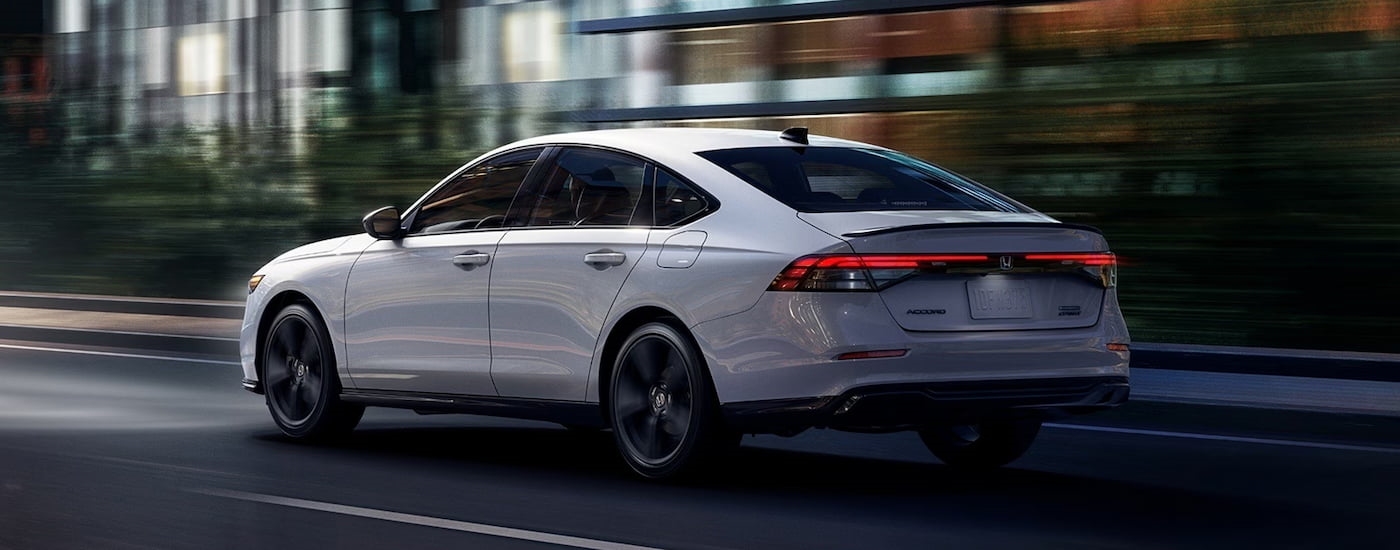 Rear of a white 2026 Honda Accord driving in a city.