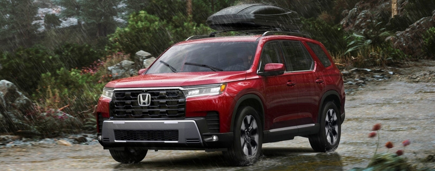 Red 2026 Honda Pilot Elite driving though the rain