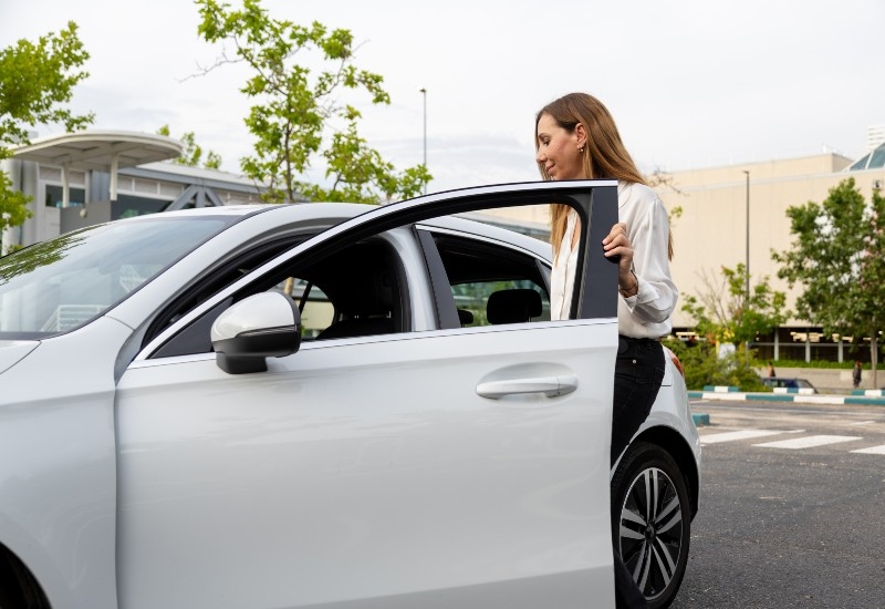 A woman stepping out of a parked car near a commercial area in Akron, OH