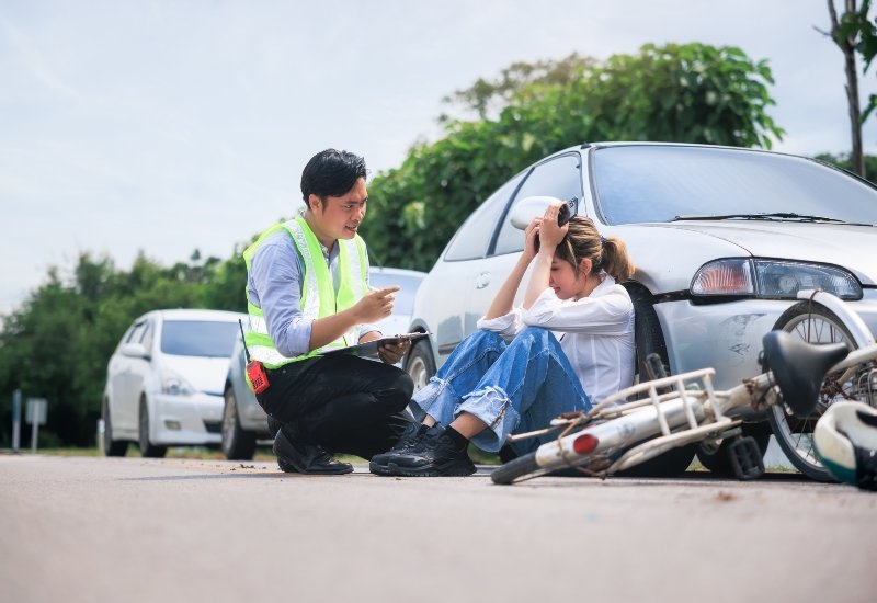 Roadside accident scene with a bicycle and a car, while assistance is provided in Akron, OH
