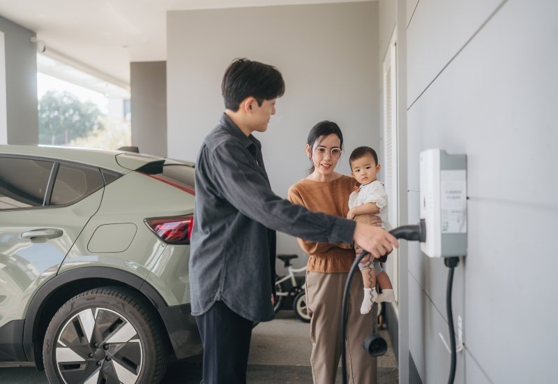 Family charging an electric vehicle at a home garage charging station in Akron, OH