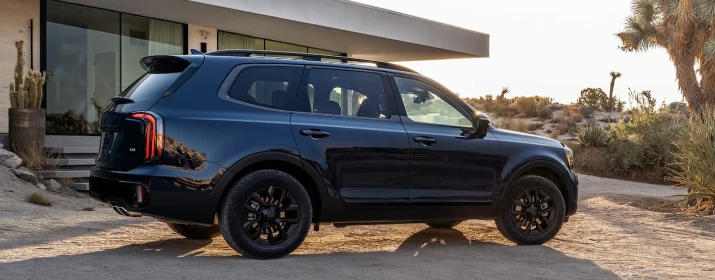 A blue 2025 Kia Telluride parked near a house.
