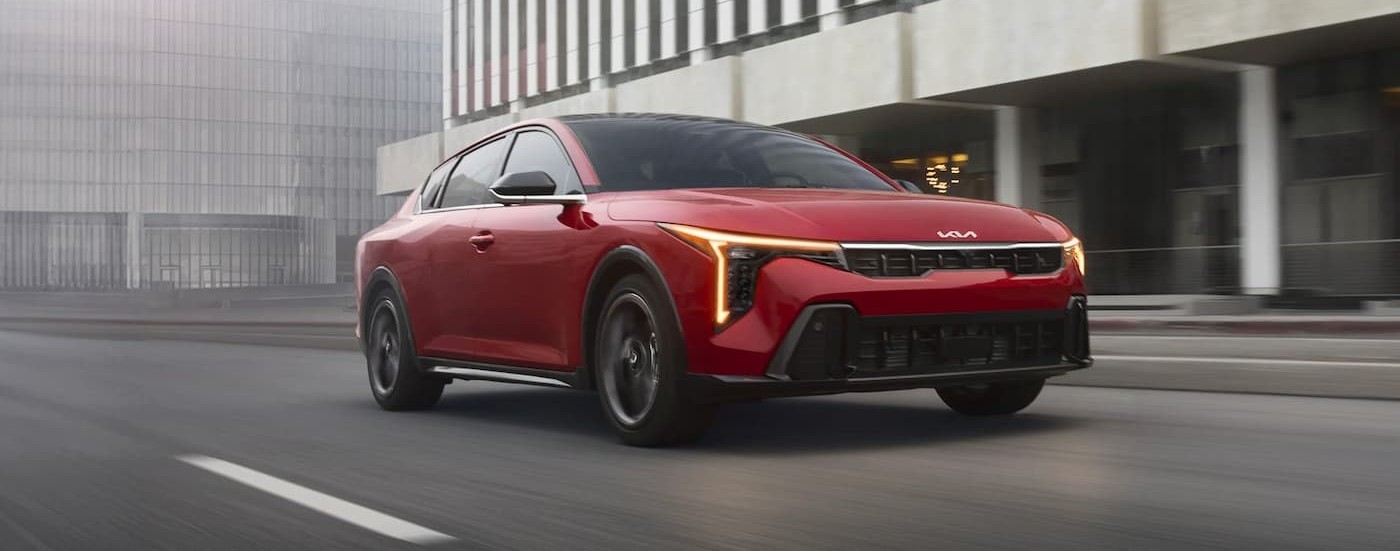 A red 2026 Kia K4 driving in a city.