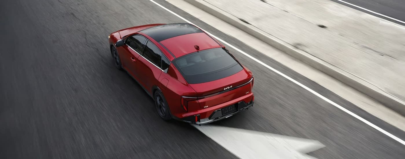 A red 2026 Kia K4 driving in a city.