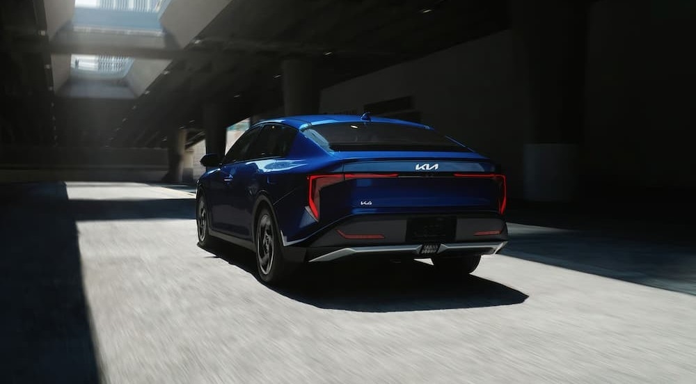 A blue 2026 Kia K4 driving in a city.