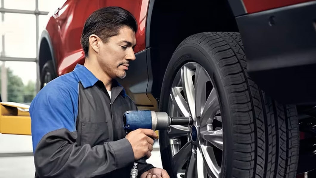 Technician performing tire rotation during Road Ready service at Murgado Ford of Chicago
