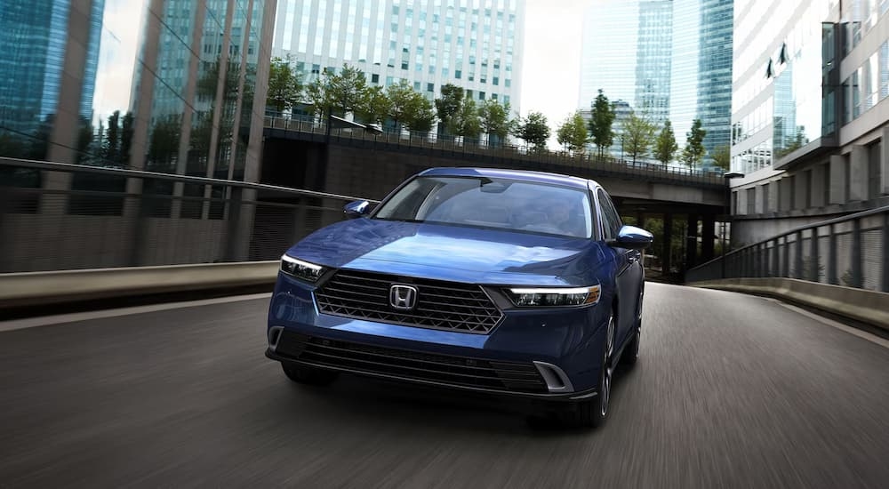 Blue 2026 Honda Accord Hybrid driving down a city street.