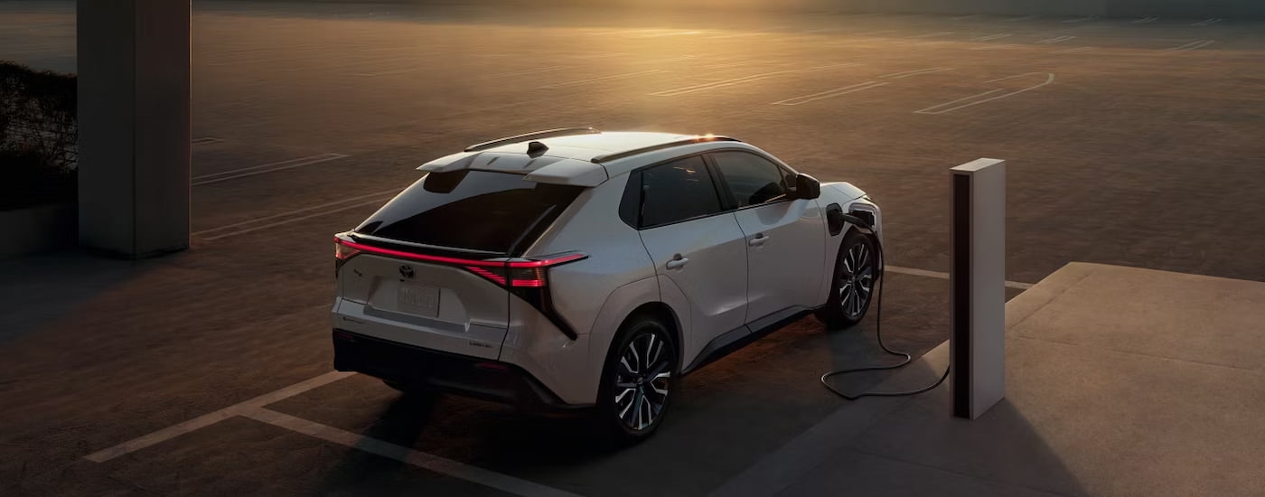 Rear of a white 2026 Toyota bZ parked at a charging station.