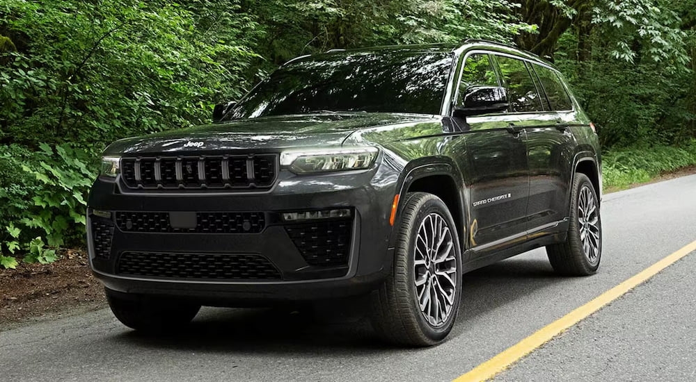 Black 2026 Jeep Grand Cherokee driving down a road.