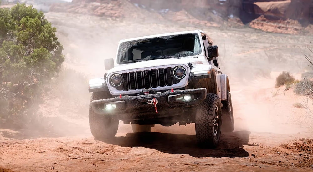 White 2026 Jeep Wrangler parked off-road on a hill.