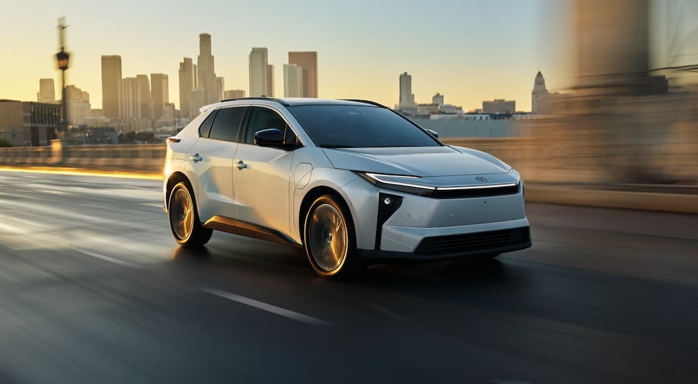 White 2026 Toyota bZ driving down a road.