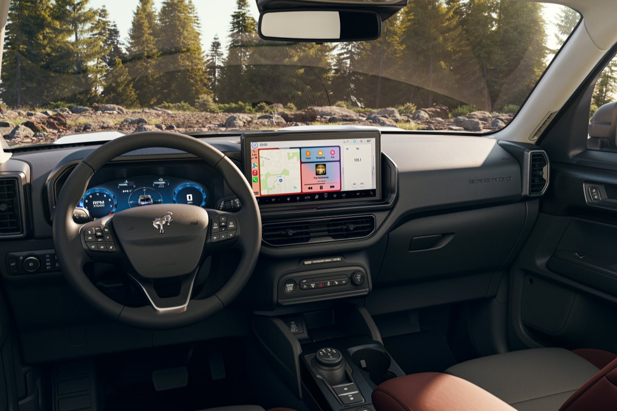 Interior view of a Ford Bronco Sport featuring a modern infotainment touchscreen, digital driver display, and smartphone connectivity, highlighting technology and comfort features designed for summer road trips and everyday travel.