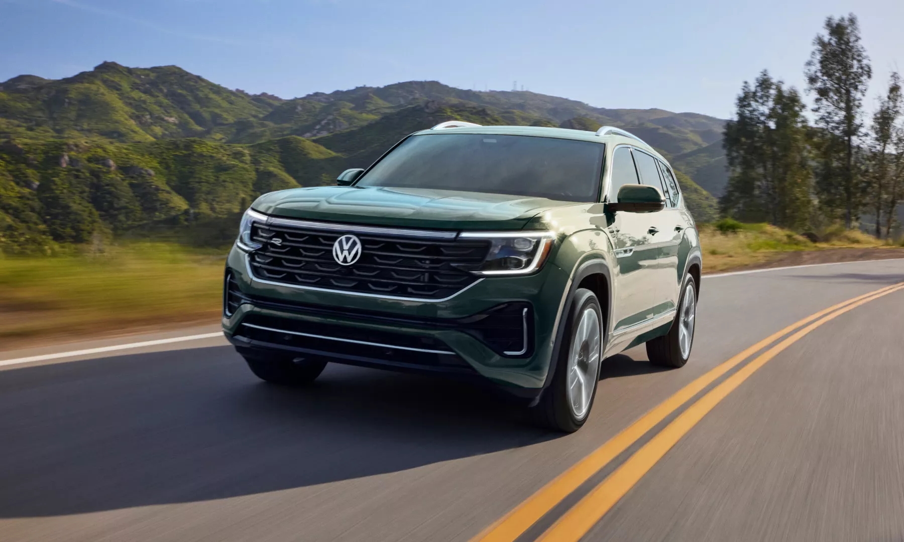 Green 2026 Volkswagen Atlas driving down mountain road