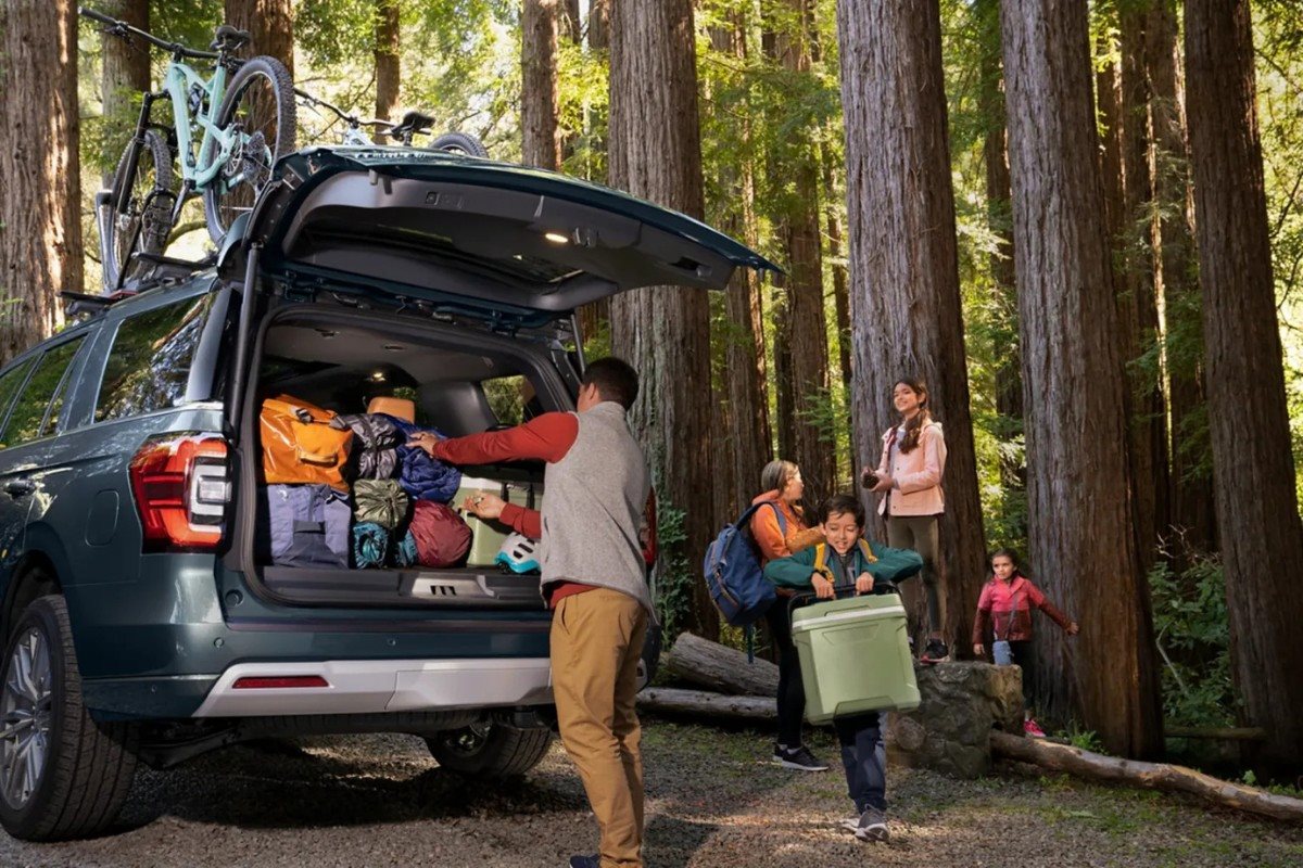 Family unloading camping gear and luggage from a Ford SUV in a forest campground,
highlighting cargo space, outdoor versatility, and family-friendly features for summer road trips
and travel adventures.