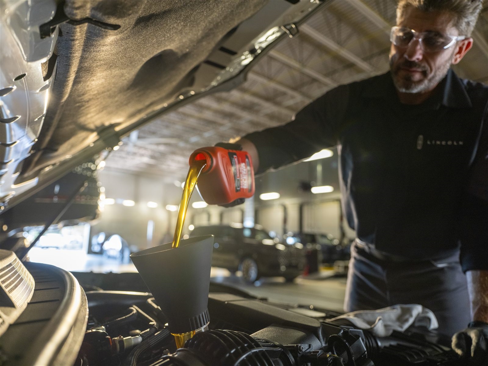 Technician pouring oil during Lincoln oil change service