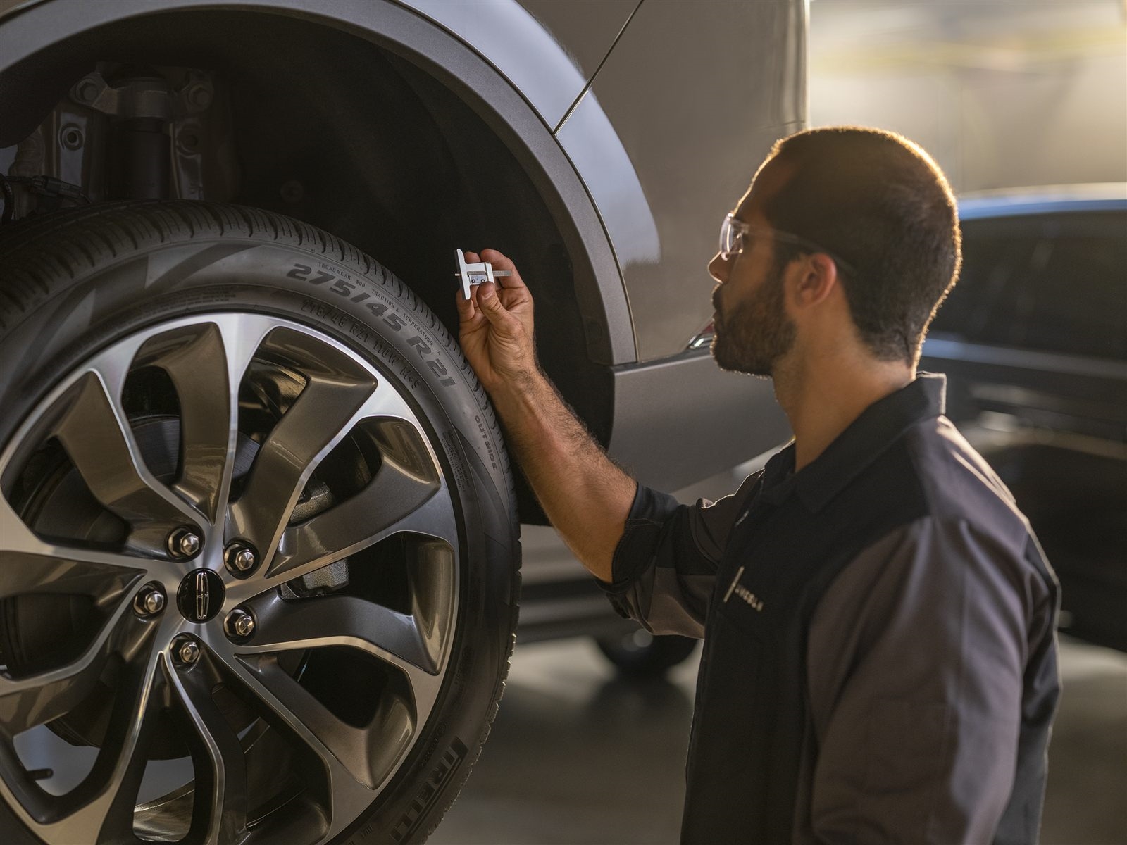 Technician checking tire tread depth during Road Ready service
