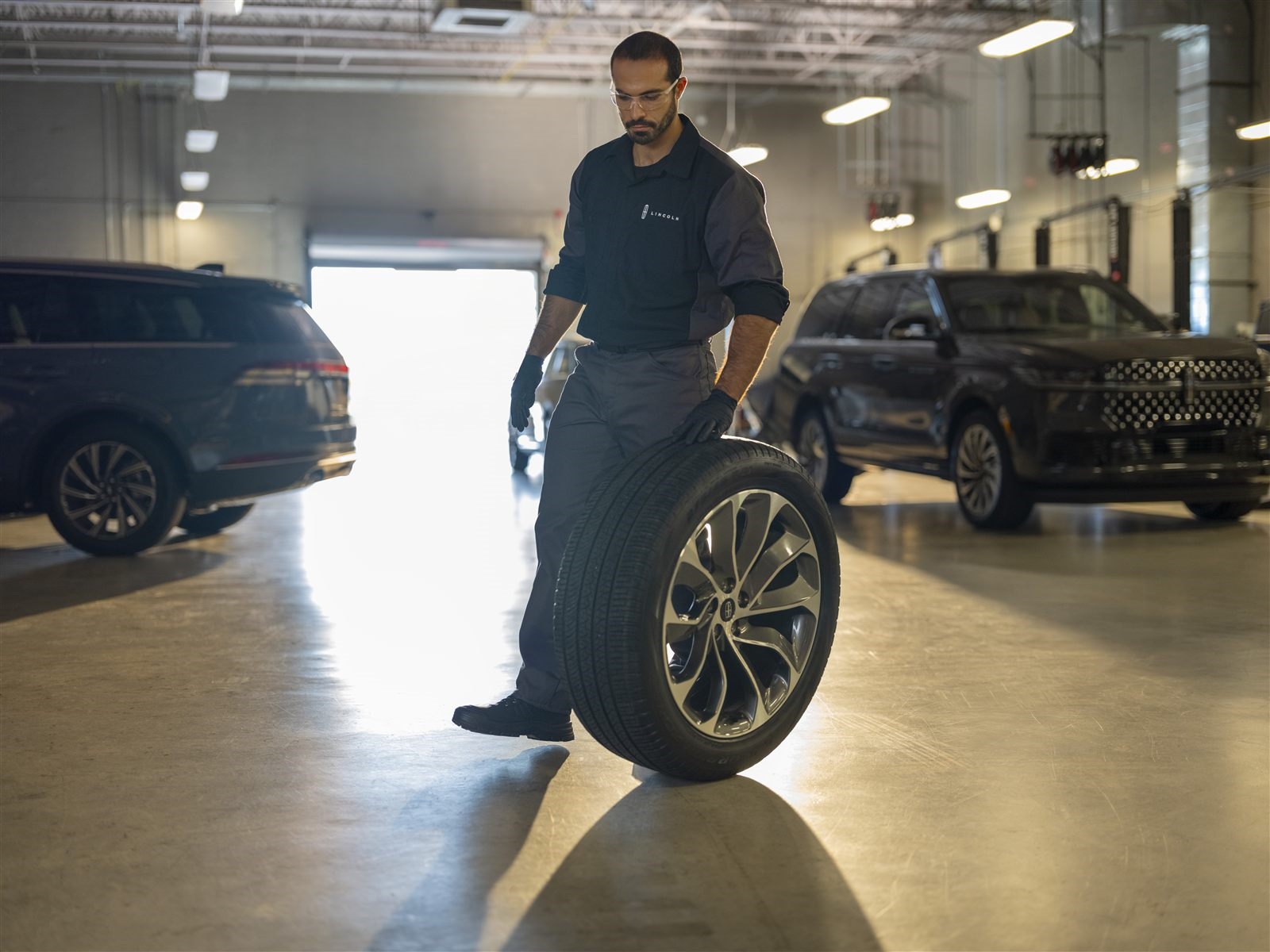 Technician with tire and wheel for Road Ready alignment service