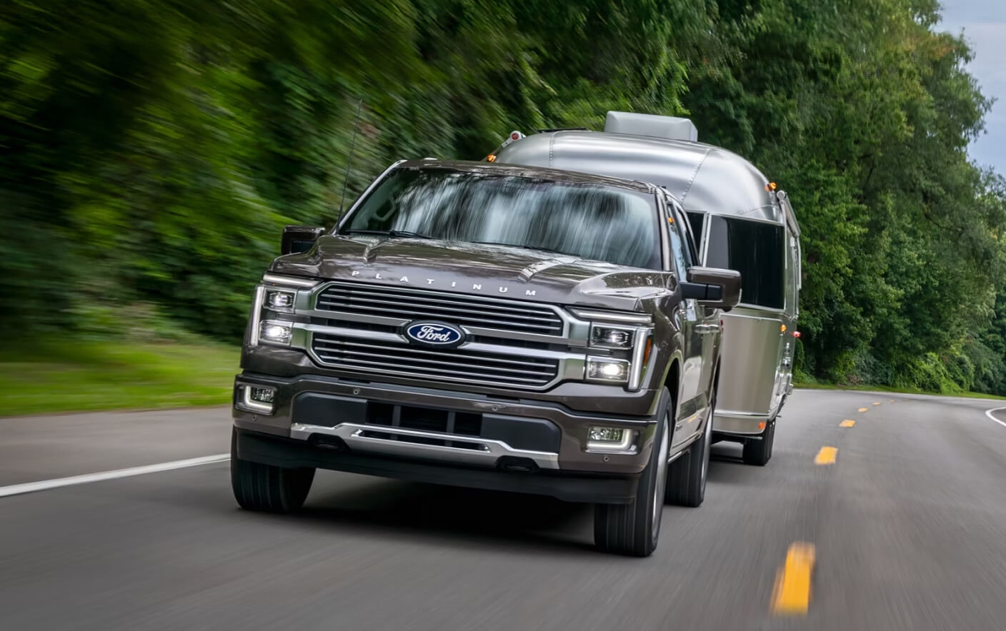 A 2026 Ford F-150® Platinum® truck in Marsh Gray pulling a camper