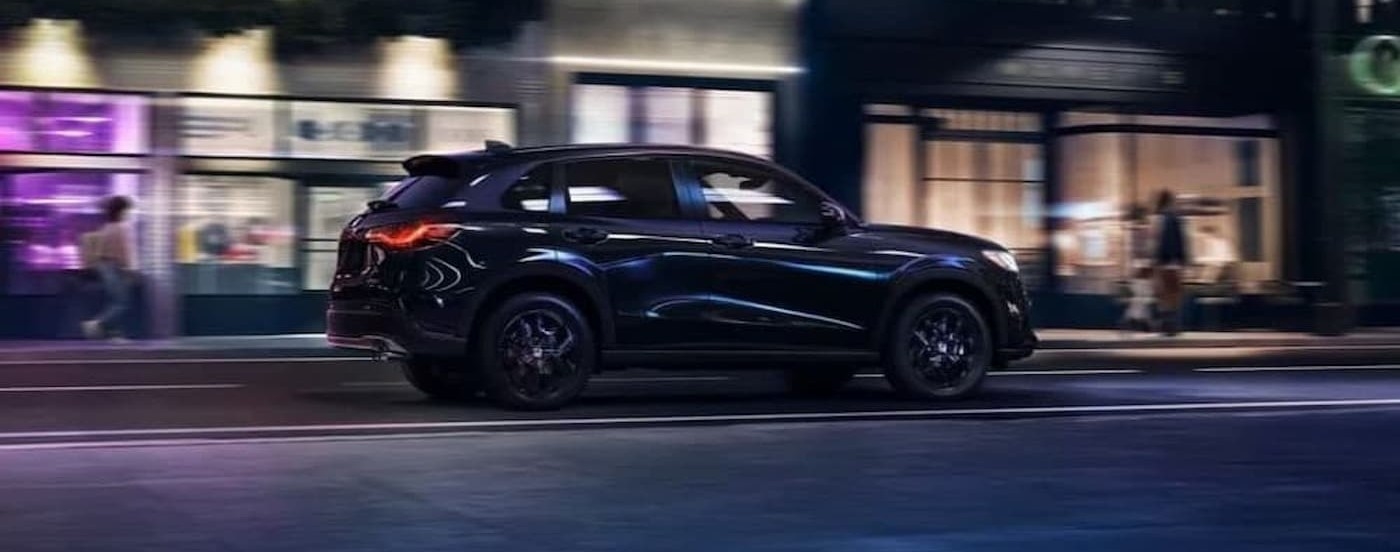 A black 2023 Honda HR-V driving in a city at night.