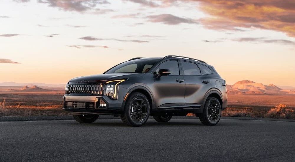 A gray 2026 Kia Sportage Plug-In Hybrid parked near a desert.