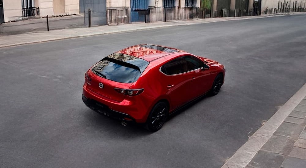A red 2026 Mazda3 Hatchback driving in a city.