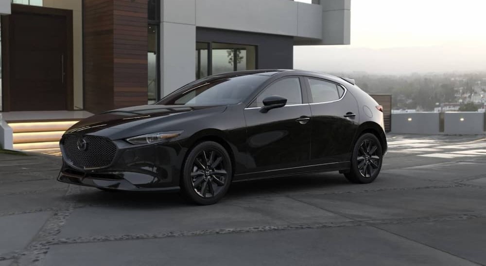 A black 2026 Mazda3 Hatchback parked near a house.