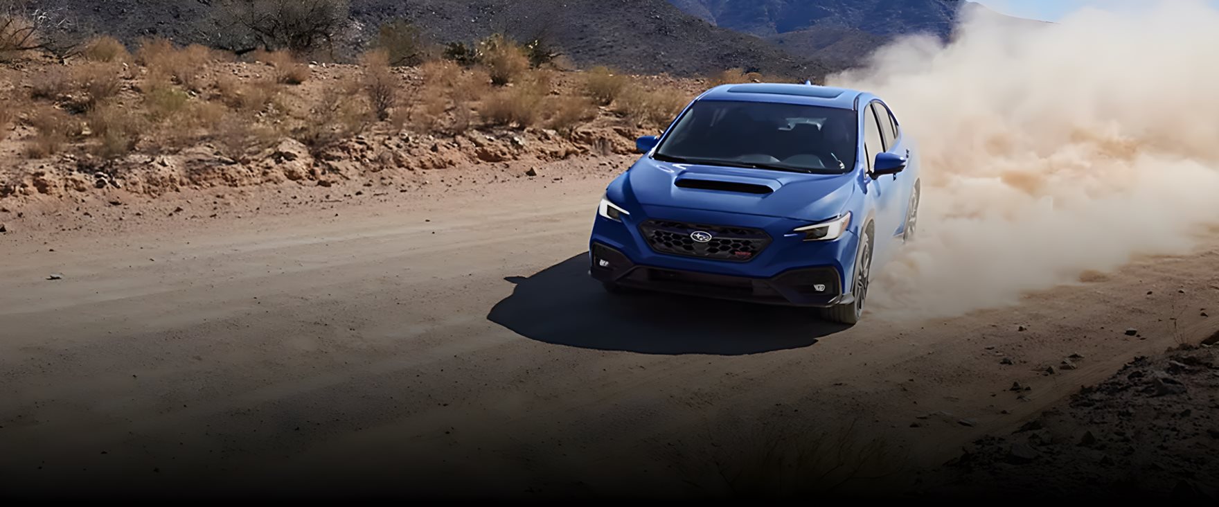 Subaru WRX rally car kicking up dirt on a rally stage showcasing Symmetrical All-Wheel Drive heritage