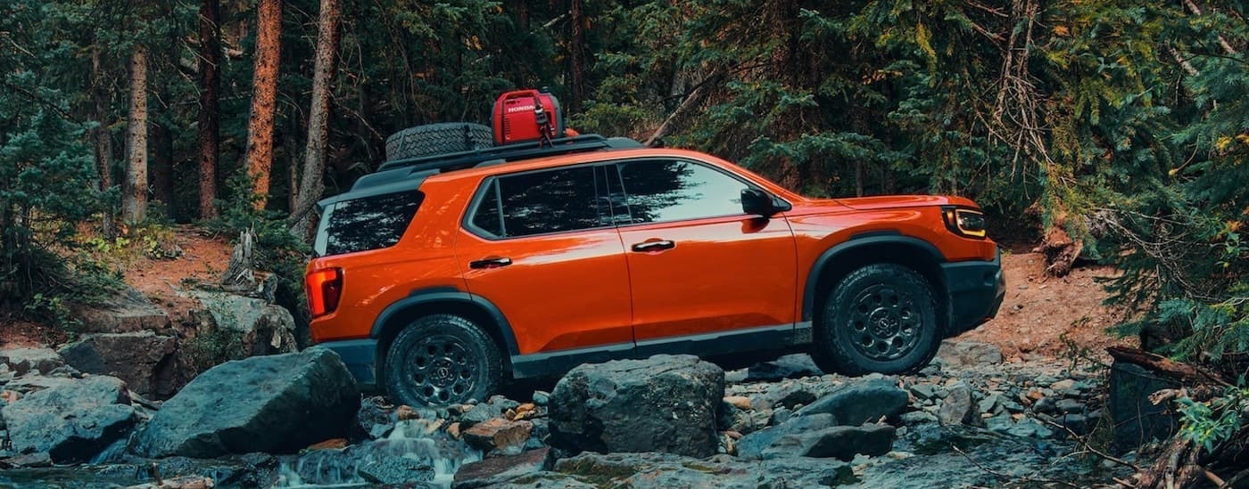 An orange 2026 Honda Passport TrailSport Elite off-roading.