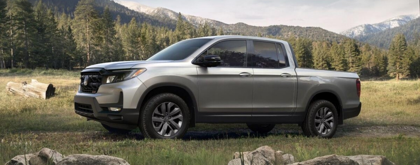 Side of a silver 2026 Honda Ridgeline parked off-road.