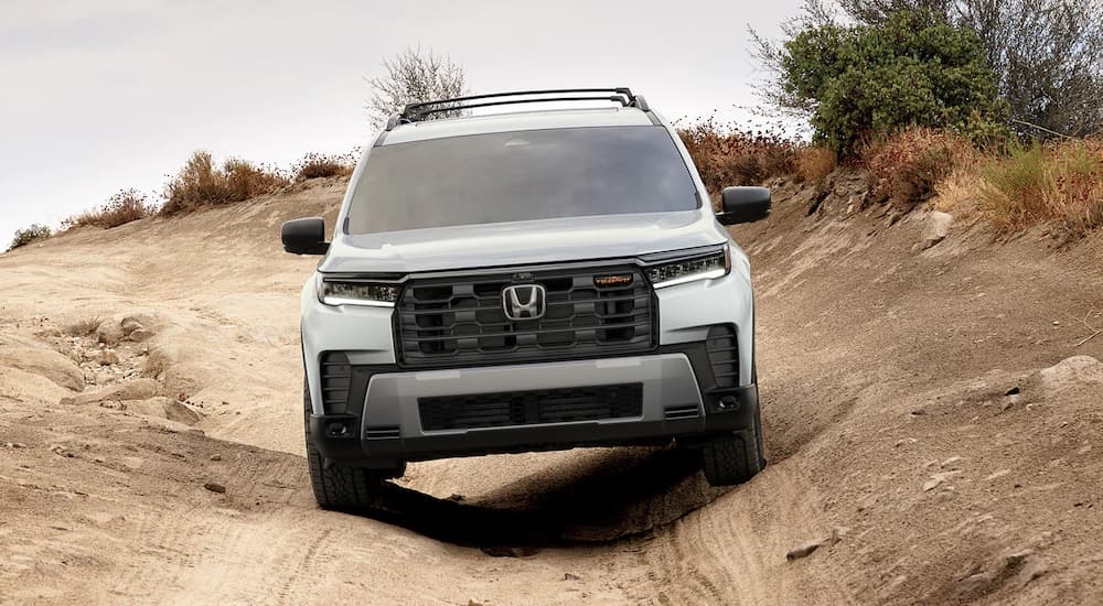 White 2026 Honda Pilot driving off-road down a hill.