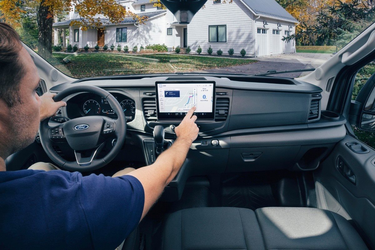 Driver interacting with the touchscreen infotainment system inside a Ford Transit commercial vehicle, highlighting modern technology and connectivity features.