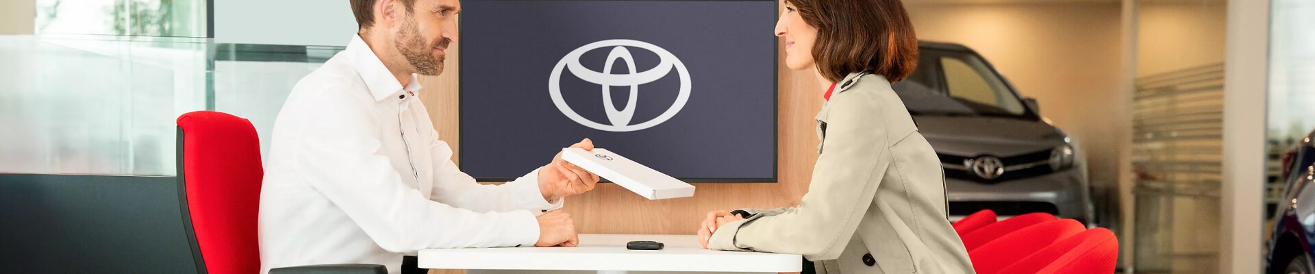 Toyota dealership showroom featuring a consultant and client discussing a vehicle purchase.