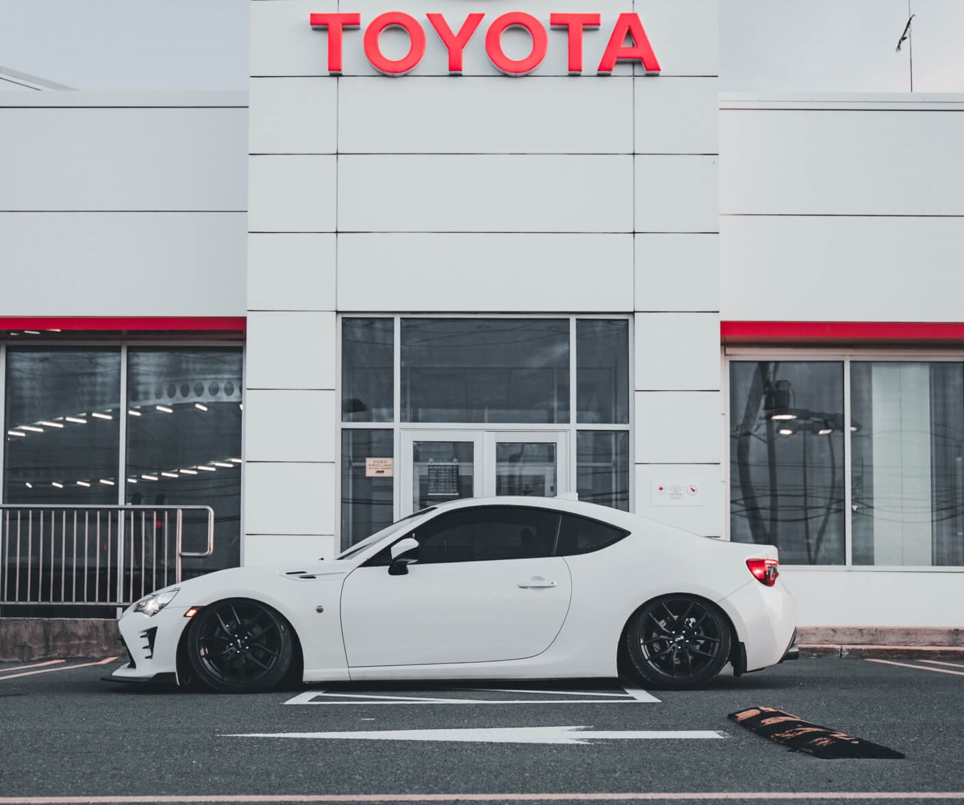Toyota 86 Base lowered coupe parked in front of a dealership building.