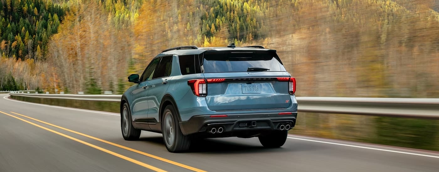 Rear of a blue 2026 Ford Explorer driving down an open road.