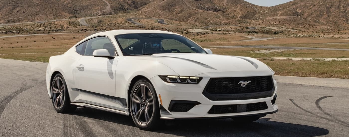 White 2026 Ford Mustang driving on a road.