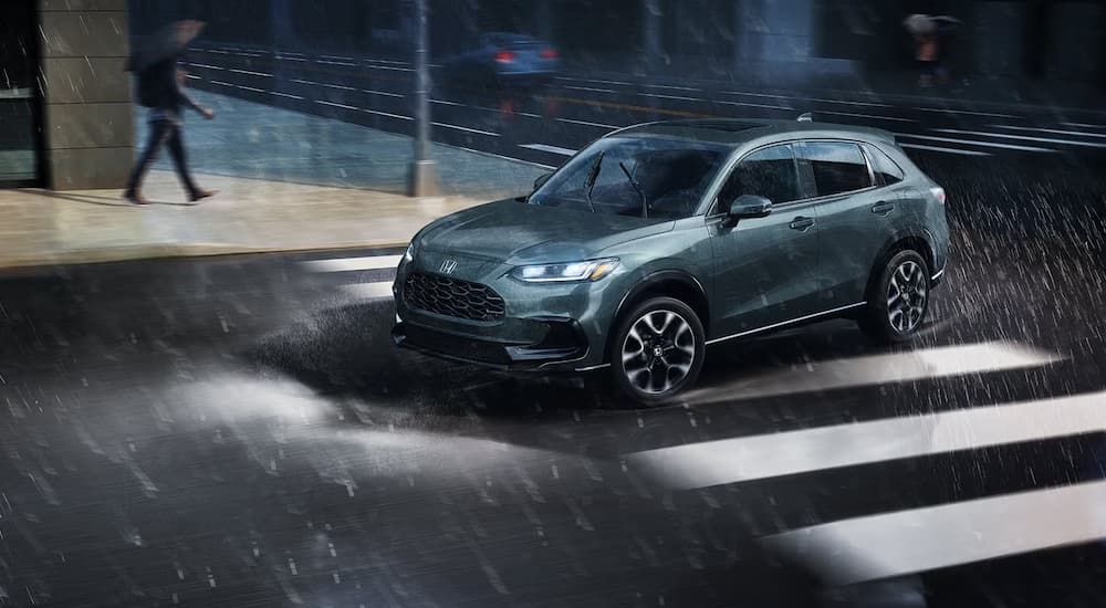Green 2027 Honda HR-V driving down a city street.