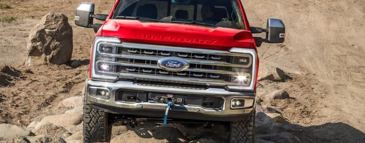 A red 2026 Ford Super Duty off-roading on rocks