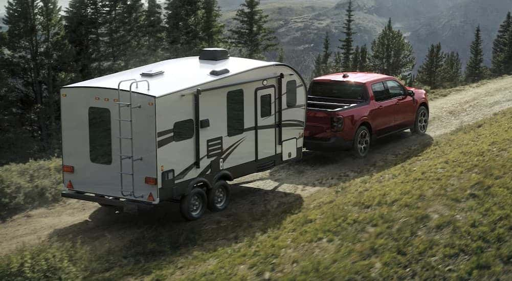 A red 2025 Ford Maverick towing a trailer