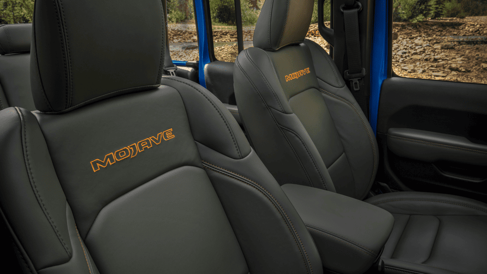 2026 Jeep Gladiator Mojave interior in Margate FL with black leather front seats embroidered with orange Mojave logo and orange contrast stitching with blue door panel visible