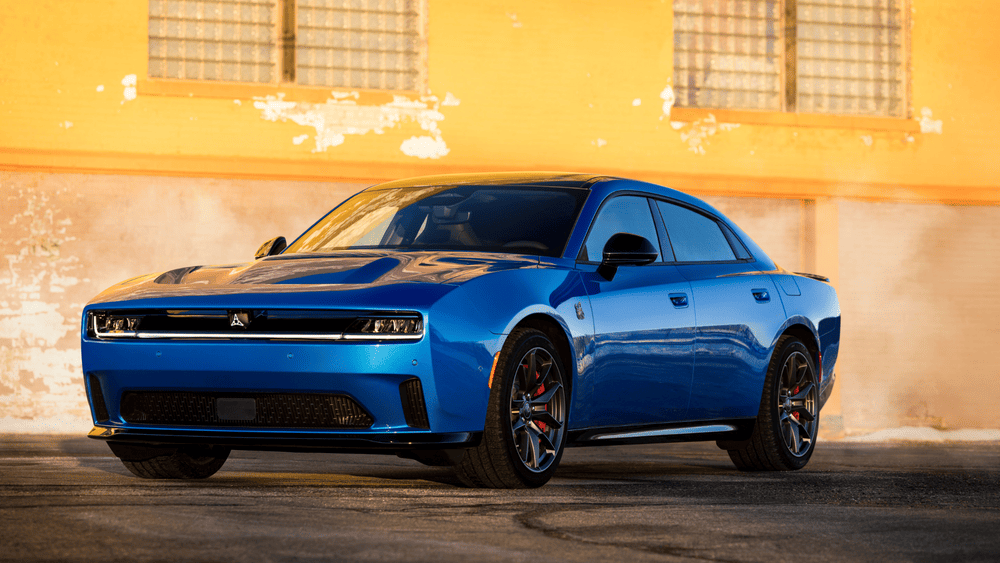 2026 Dodge Charger Daytona interior in Margate FL featuring bold red performance seats, Dodge-branded flat-bottom steering wheel, wide touchscreen infotainment, and carbon fiber trim accents