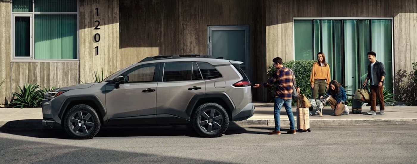 People standing near the tailgate of a gray 2026 Toyota RAV4.