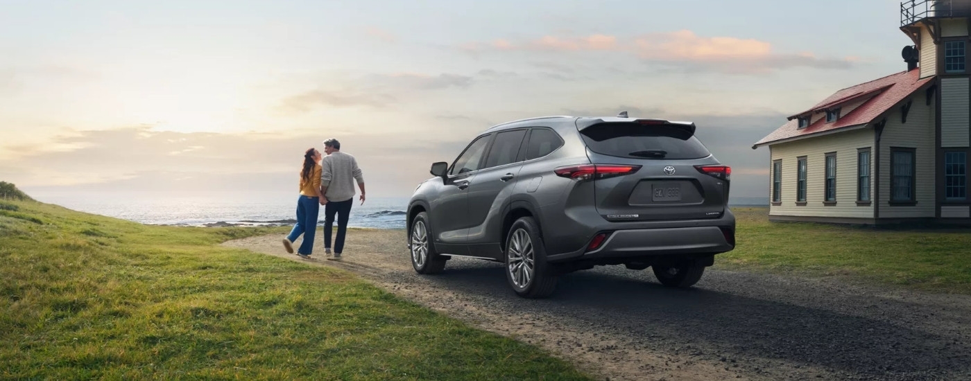 Grey 2025 Toyota Highlander Hybrid Limited 25th Edition parked near a couple